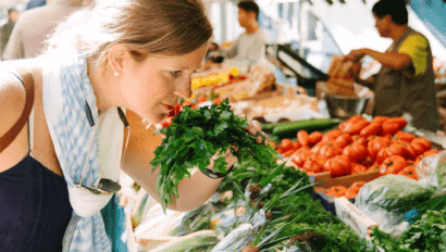 A woman smells the fresh herbs at a Parisian food market