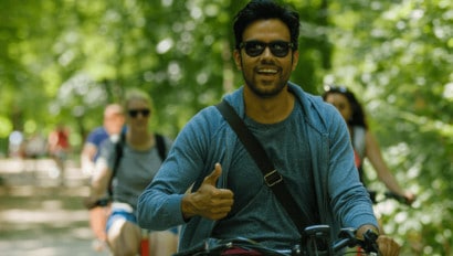 A man gives a 'thumbs up' while riding his bike through Munich, Germany