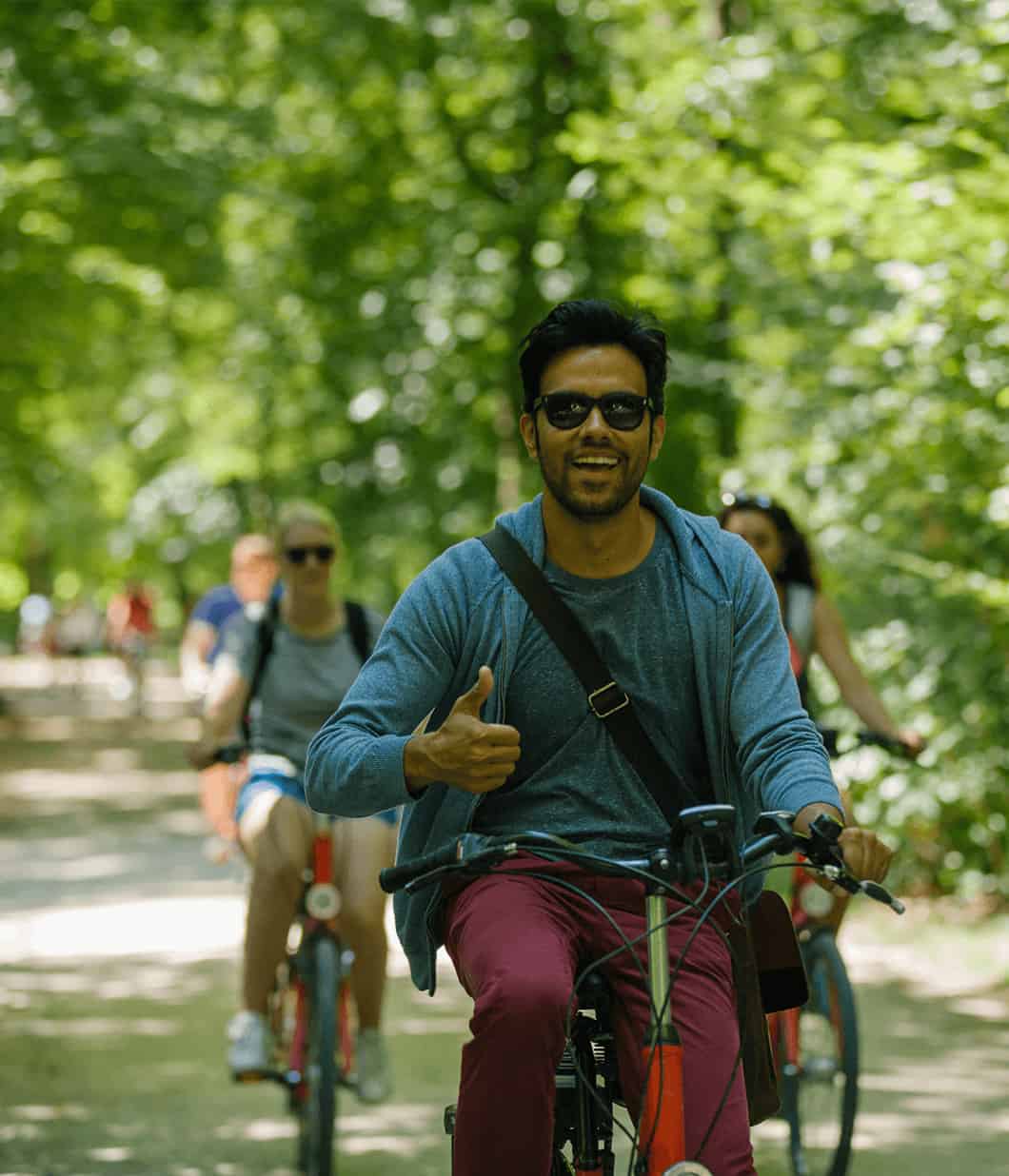 A man gives a 'thumbs up' while riding his bike through Munich, Germany