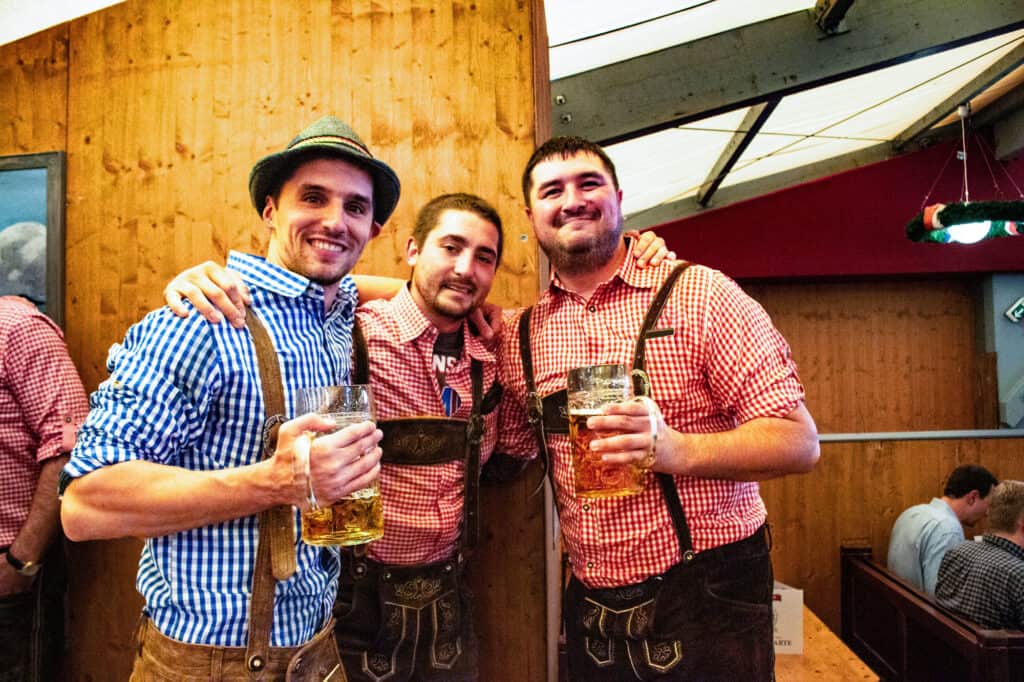 Three men at Oktoberfest drinking beers and dressed in liederhosen