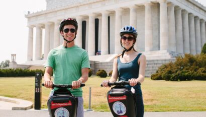 A couple poses for a photo on Segways in front of the Lincoln Memorial in Washington, D.C.