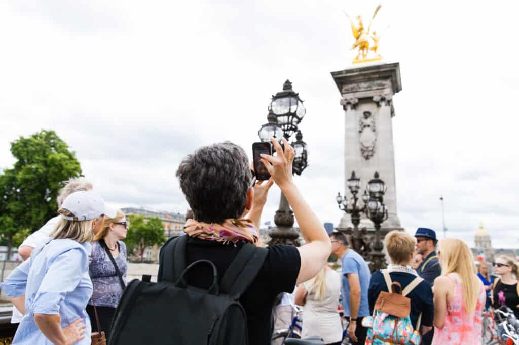 Paris Alexandre III bridge with tourists on the bridge taking photos