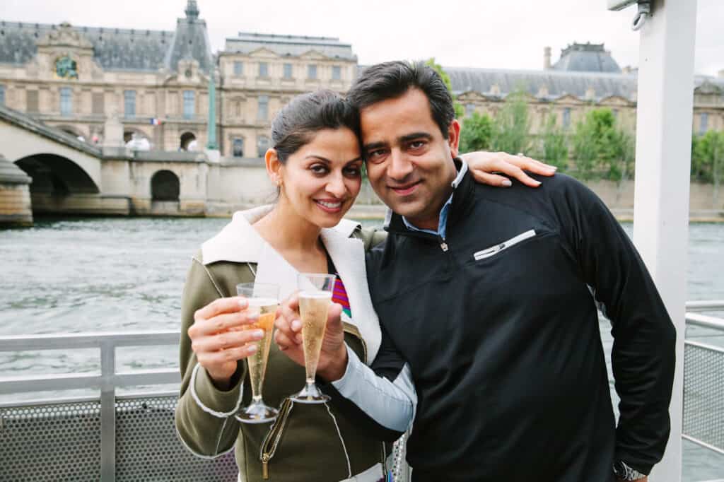 A couple toasts with champagne on a boat in Paris