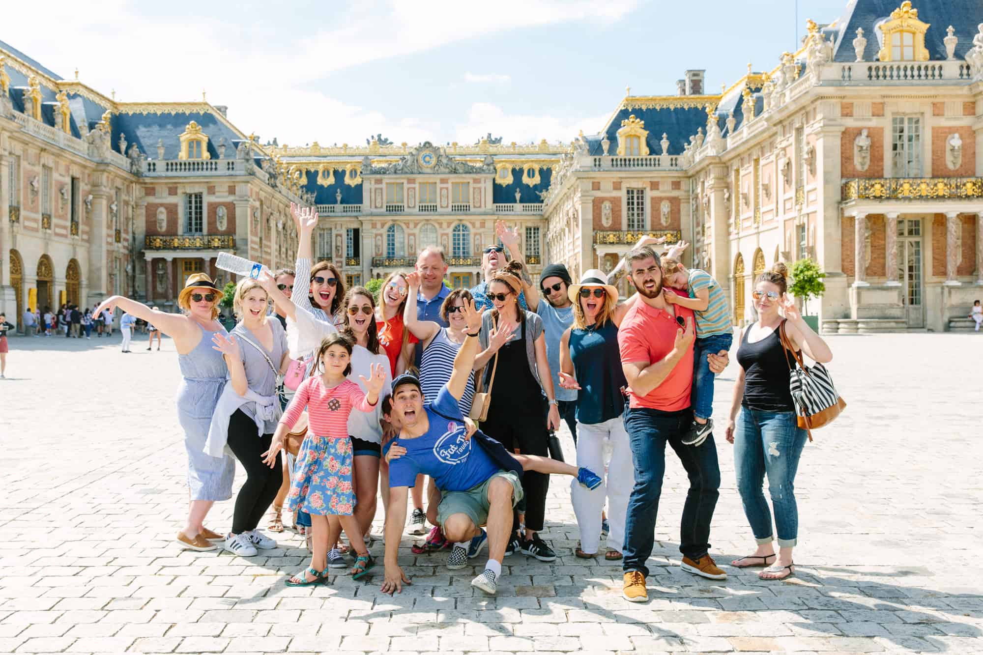 A group poses for a silly photo in front of the palace of Versailles.