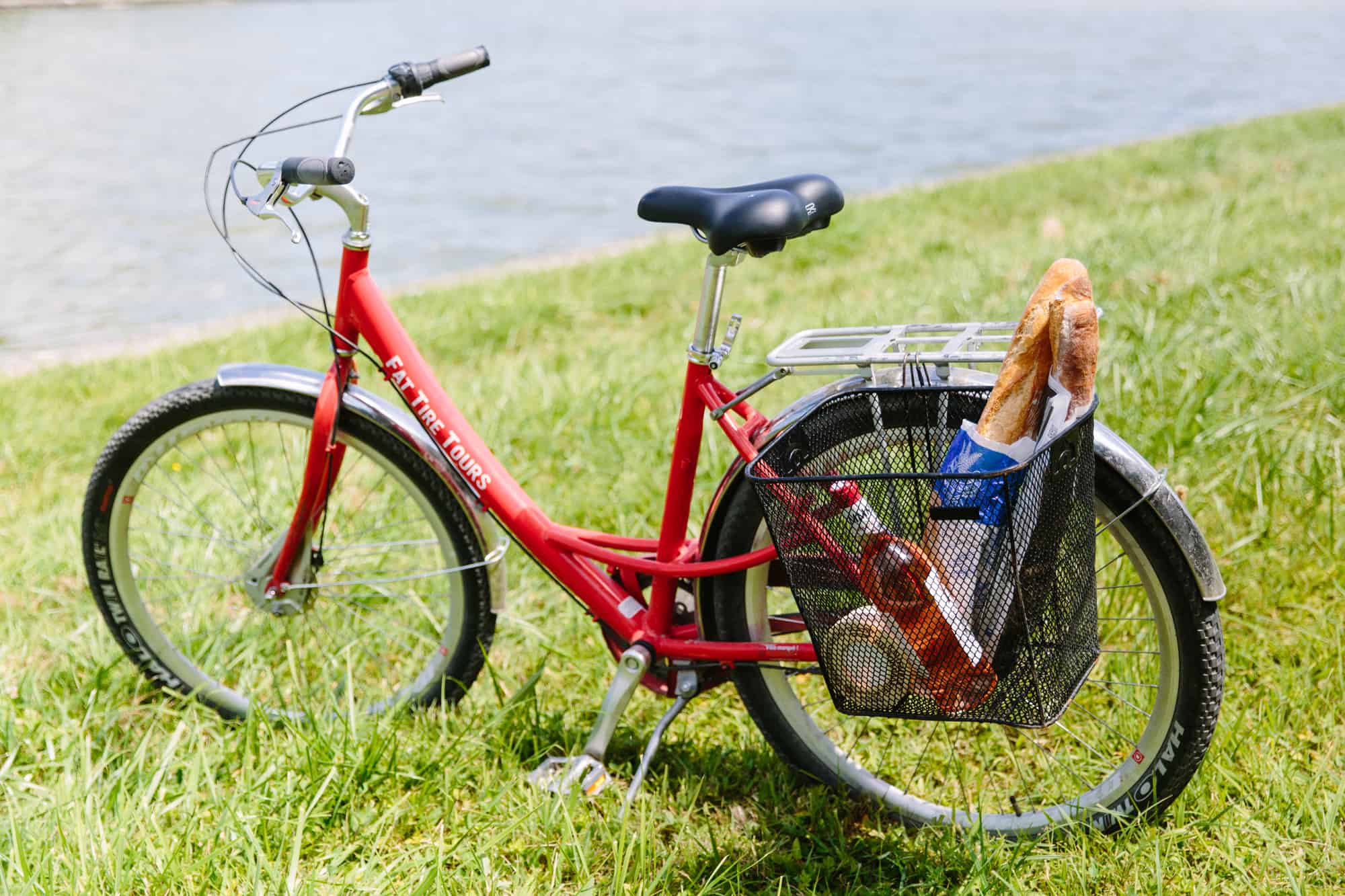 A red bicycle with a basket on the side containing a baguette in Versailles.