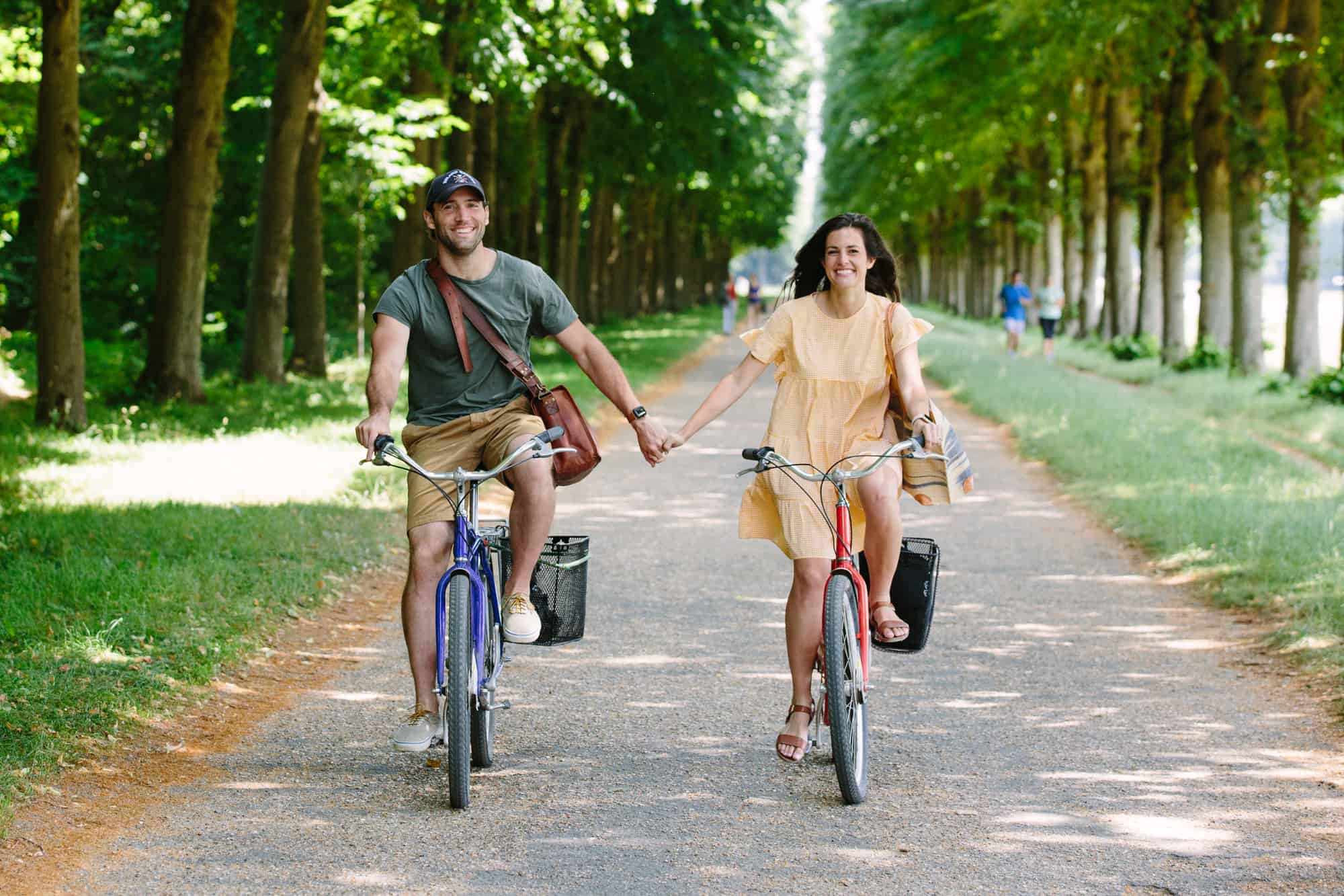 A couple holds hands as they ride under the trees in Versailles.
