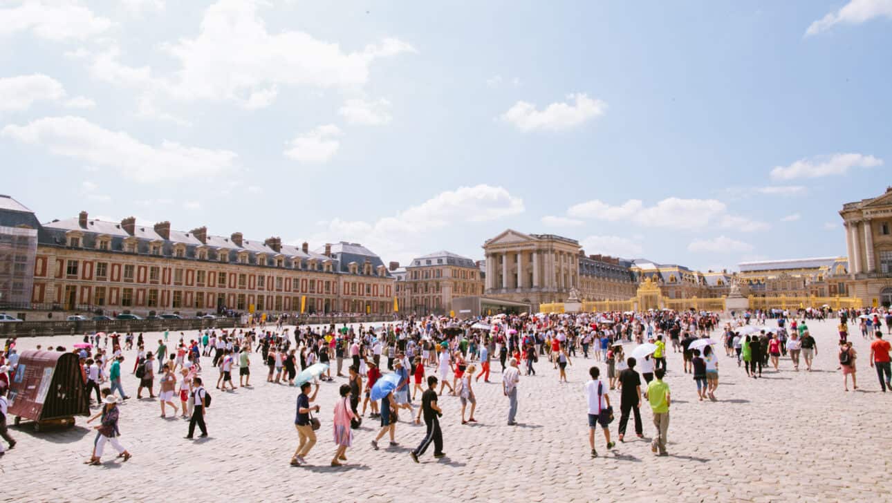 A long line forms in front of the palace of Versailles.