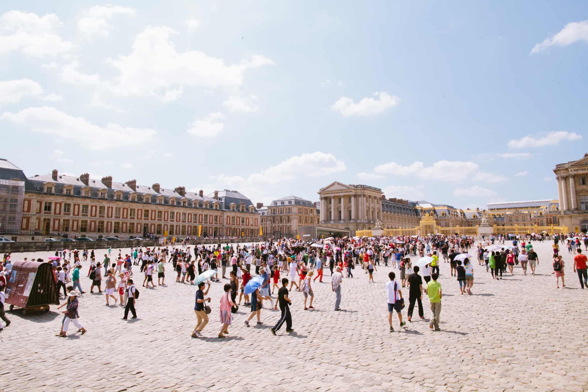 A long line forms in front of the palace of Versailles.