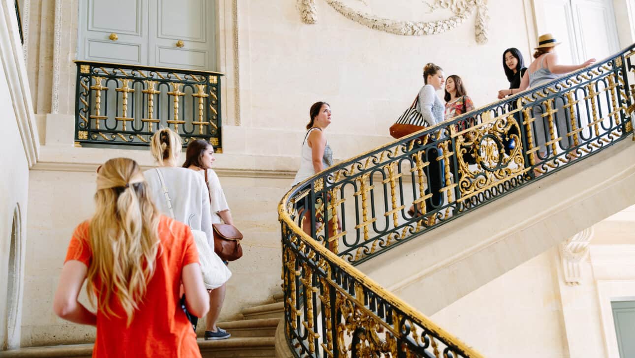 A group climbs the stairs inside the palace of Versailles.