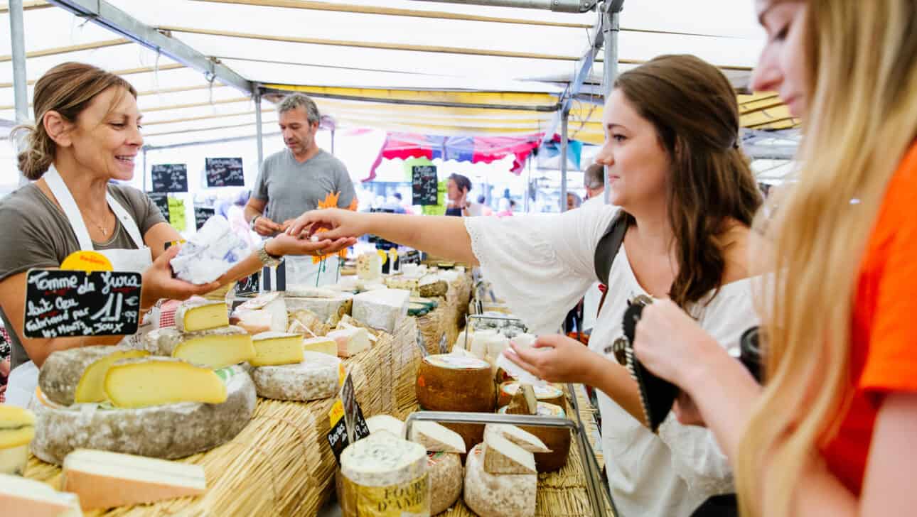 Two women purchase cheese at the open-air market in Versailles, France.