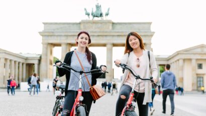 Two girls pose with their bikes in front of the Brandenburg Gate in Berlin, Germany
