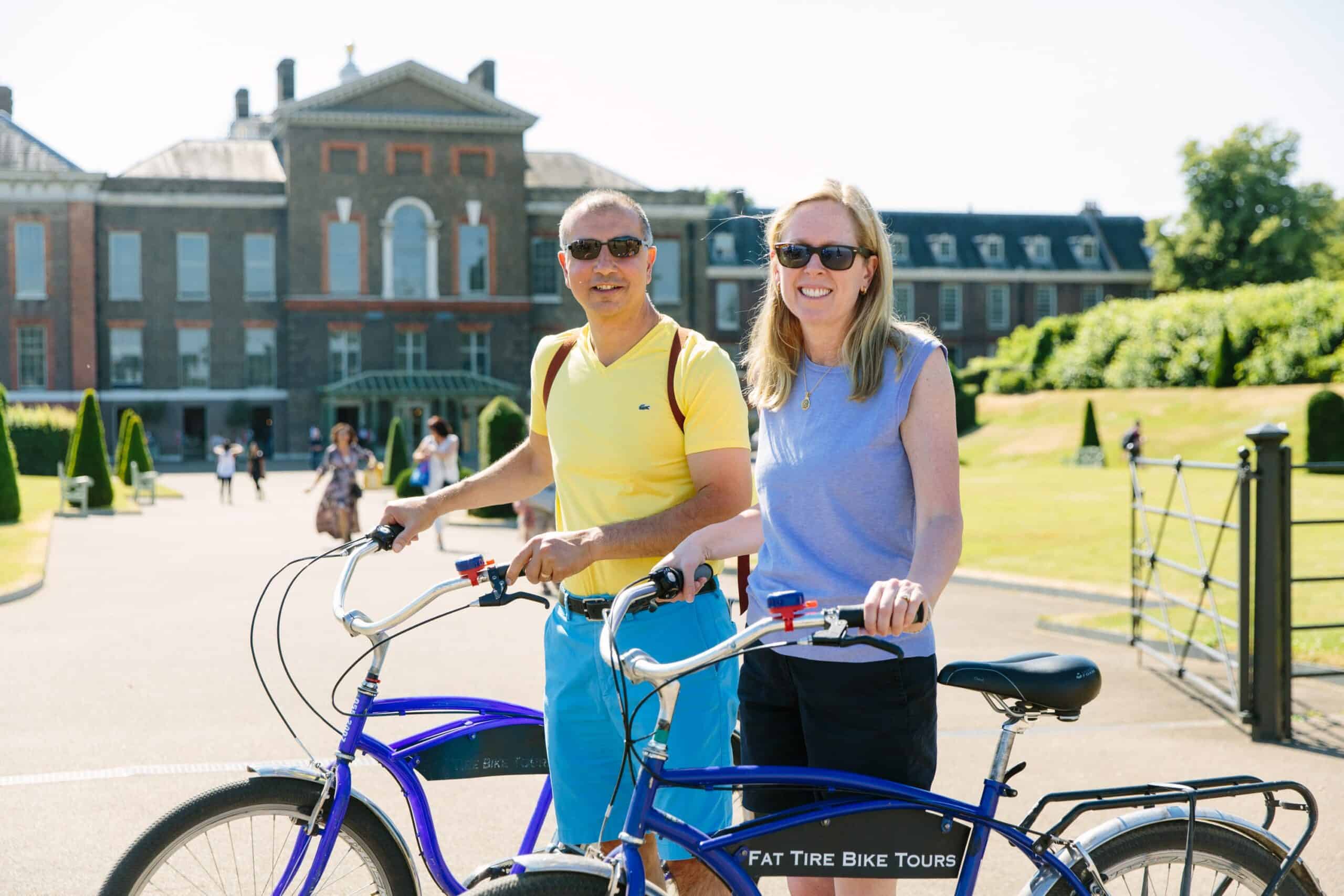 A couple poses with bikes in front of Kensington Palace in London, England