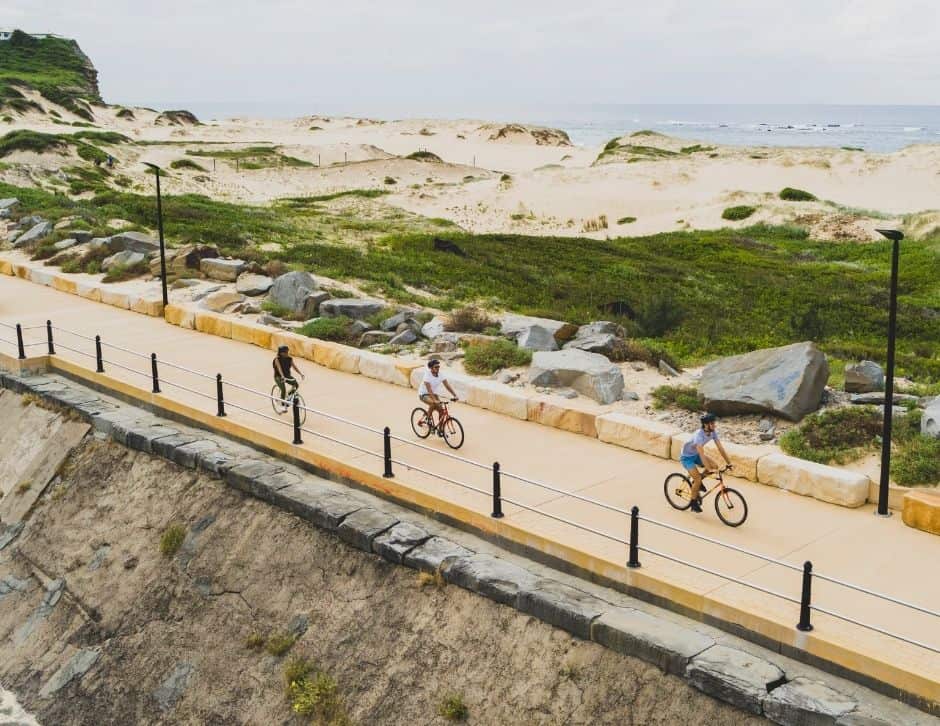 people riding bicycles on a path near the sea in Newcastle, Australia