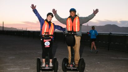 Two people happily ride Segways in front of the Golden Gate Bridge in San Francisco, California
