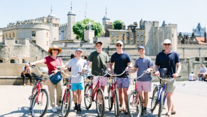 A group poses with their bikes in front of the Tower of London