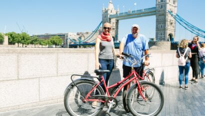 A couple poses with their bikes in front of the Tower Bridge in London, England