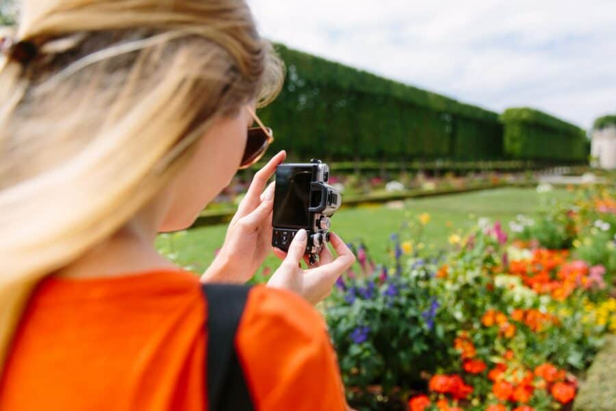 a woman photographs the flowers outside the Petit Trianon in Versailles, France