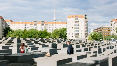 People walk through the Memorial to the Murdered Jews of Europe with the TV Tower in the background in Berlin, Germany