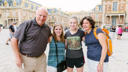 A family poses for a photo in front of the Chateau of Versailles, France
