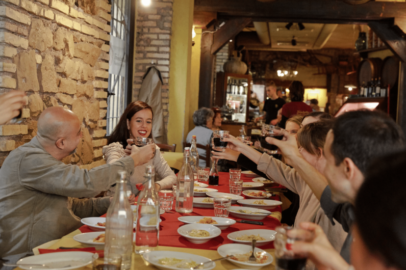 People cheersing glasses at a table with Italian specialties