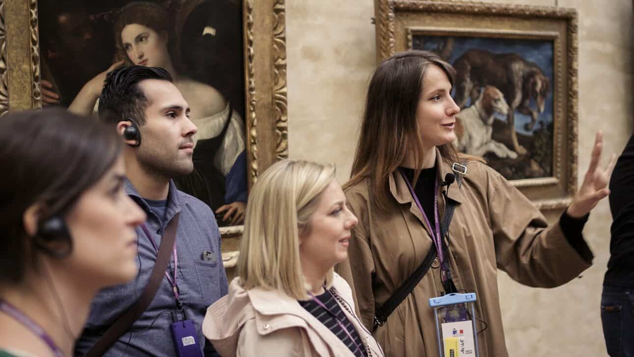 A guide leads a group around the Louvre in Paris, France