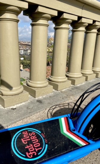 An e-scooter parked along a columned fence in Florence, Italy