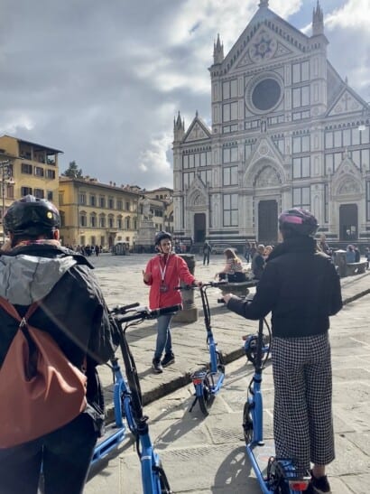 A guide explains the Santa Croce basilica to a group of e-scooter riders