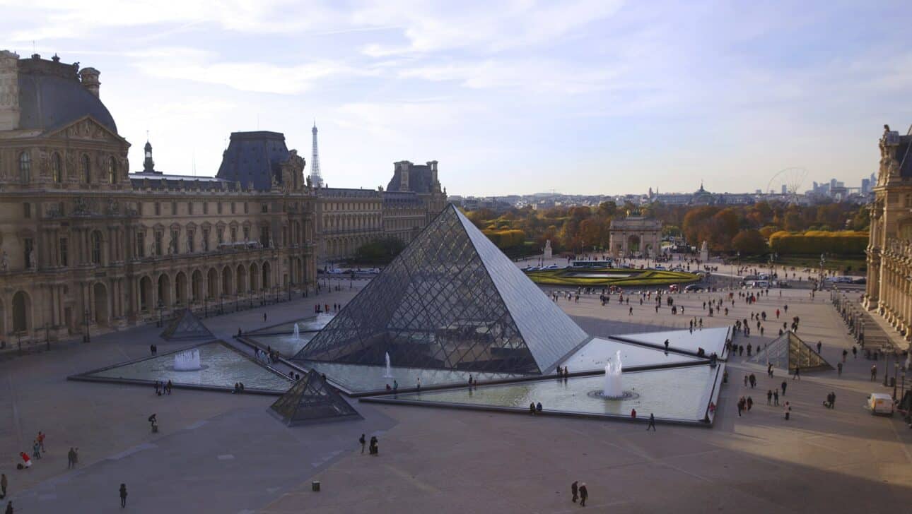 The Pyramid in the Louvre Courtyard with the Eiffel Tower in the background in Paris, France