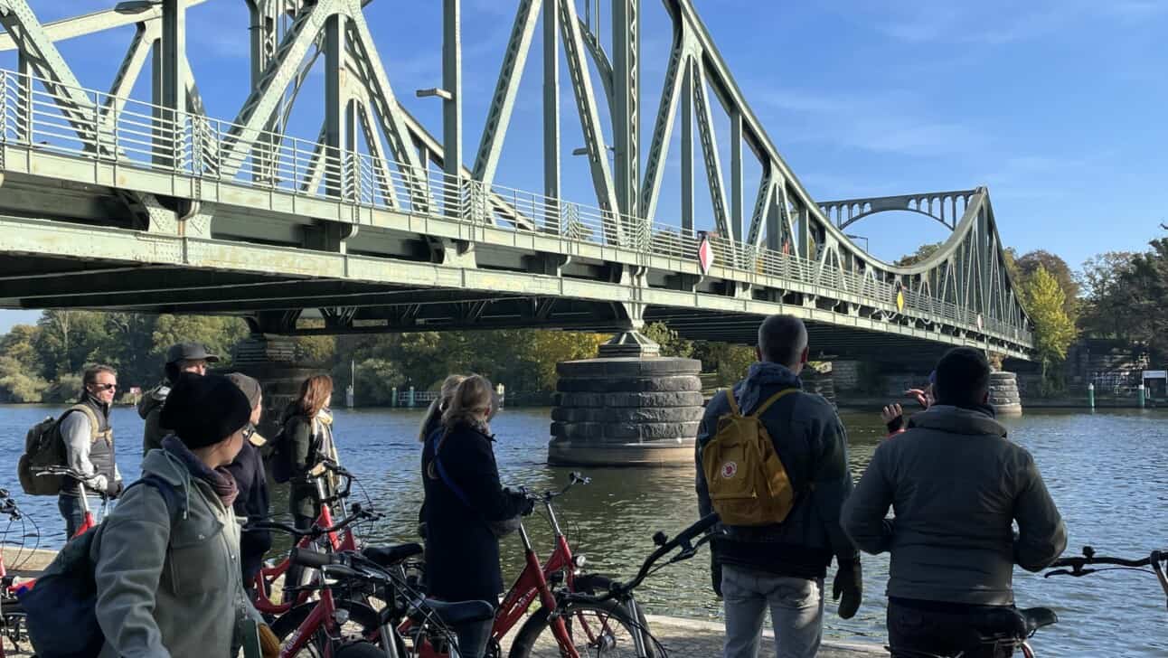 a group of cyclists stops at the bridge of spies in Potsdam