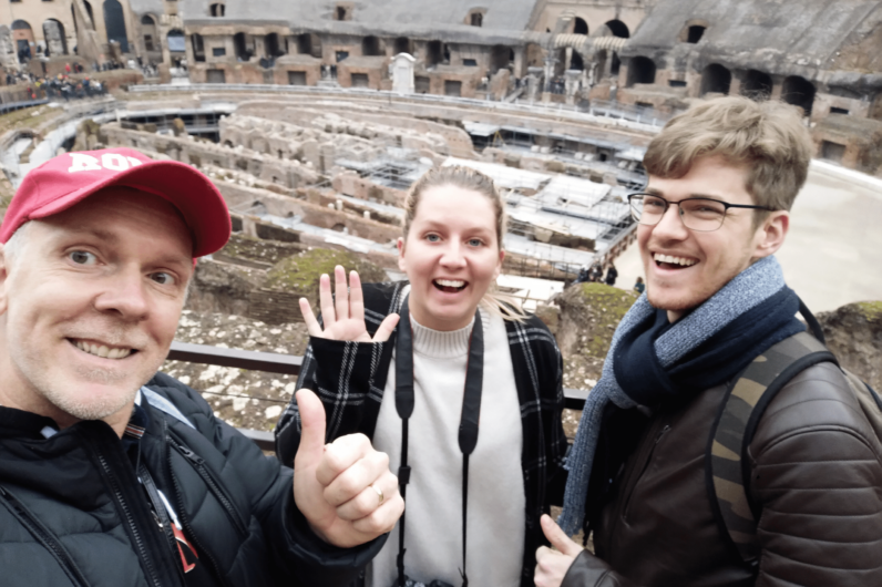 A group of three waving from inside the Colosseum in Rome