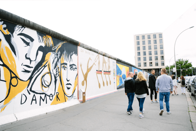 People walk alongside the Berlin Wall
