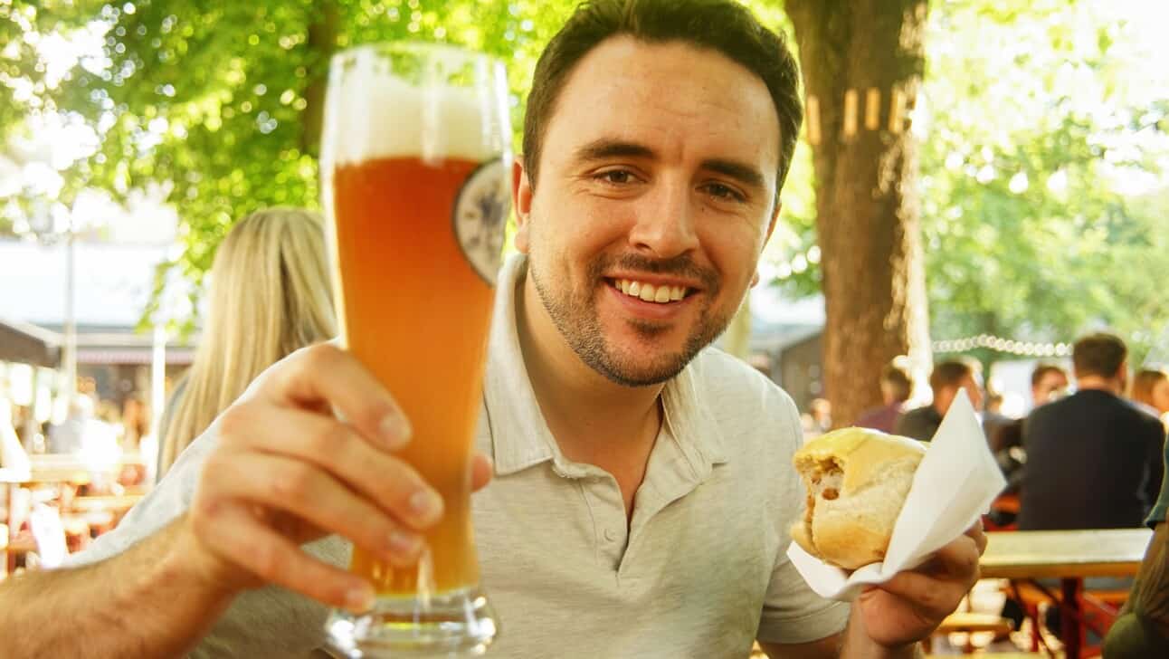 A man enjoys a beer and a bratwurst in a local Berlin beer garden