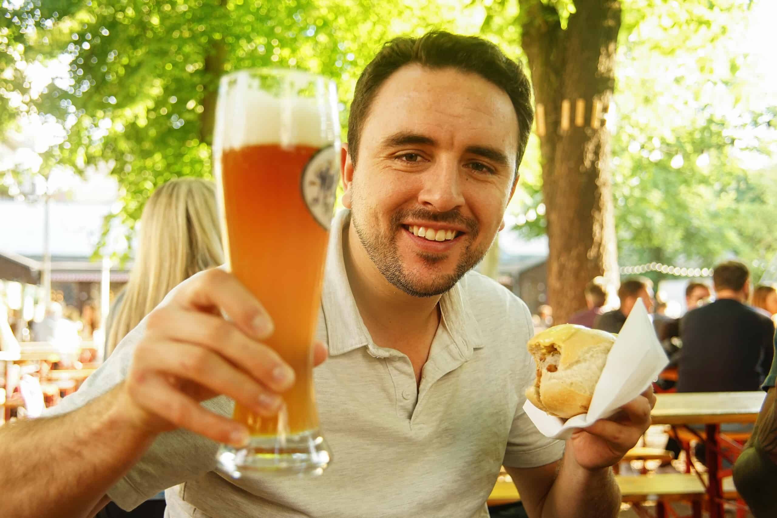 A man enjoys a beer and a bratwurst in a local Berlin beer garden