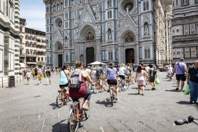 A group of cyclists rides towards the Duomo in Florence, Italy