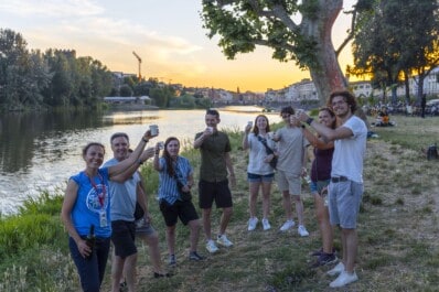A group raises their glasses for a cheers along the Arno river in Florence, Italy