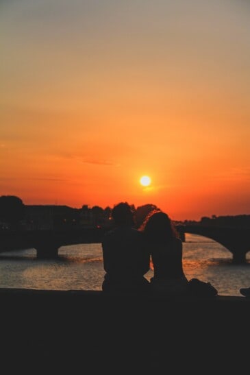 A couple watches the sunset from a bridge in Florence, Italy