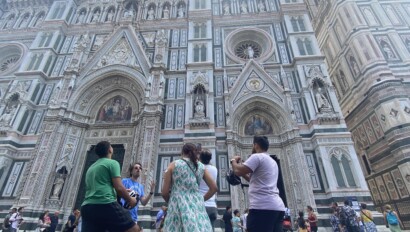 A group of people on e-scooters stop in front of the Florence Duomo