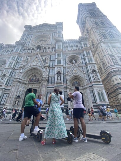 A group of people on e-scooters stop in front of the Florence Duomo
