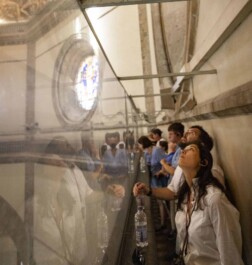 A group walks around the edge of the interior dome inside the Florence cathedral