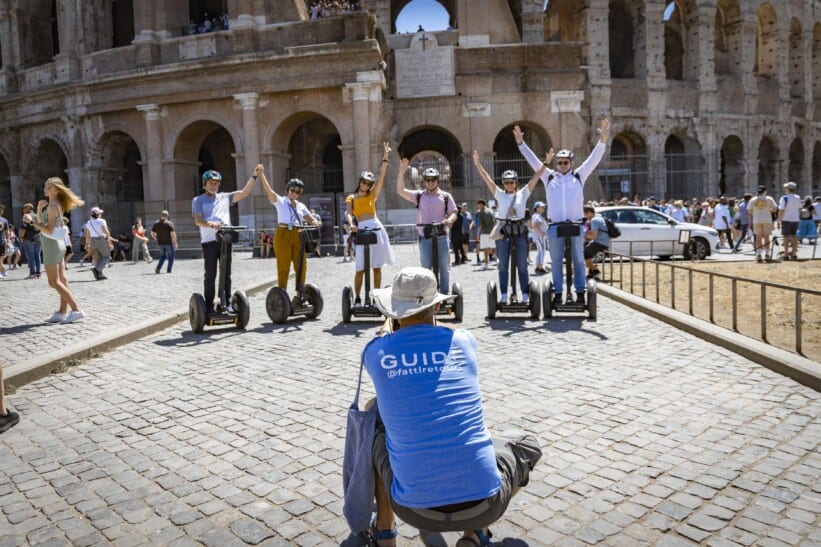 The tour guide takes a picture of the group on Segways in front of the Colosseum in Rome, Italy
