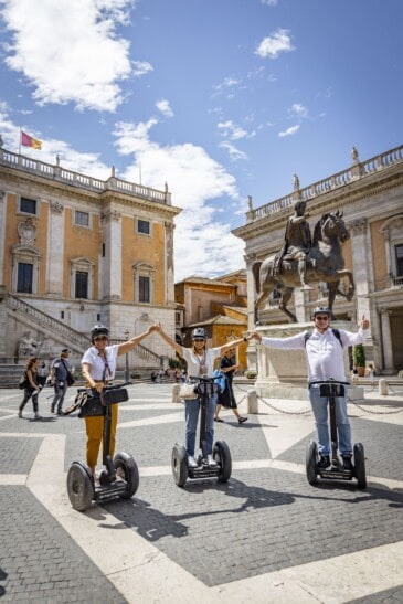 A group of Segwayers pose for a photo with their hands in the air