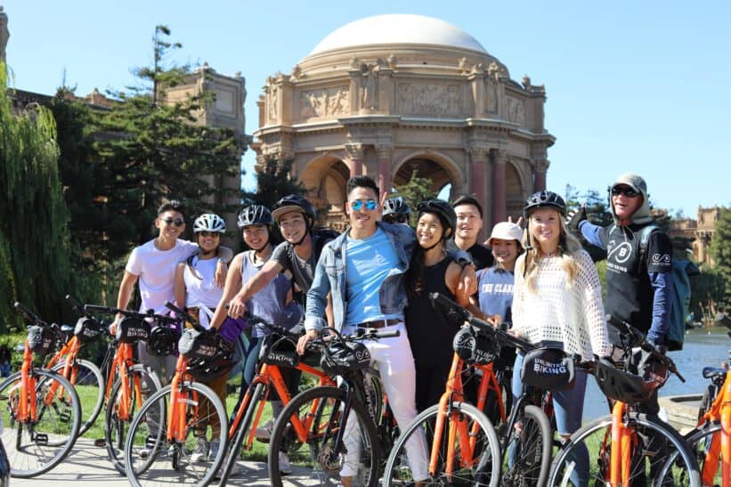 A group poses with their bikes in front of the Palace of Fine Arts in San Francisco, California