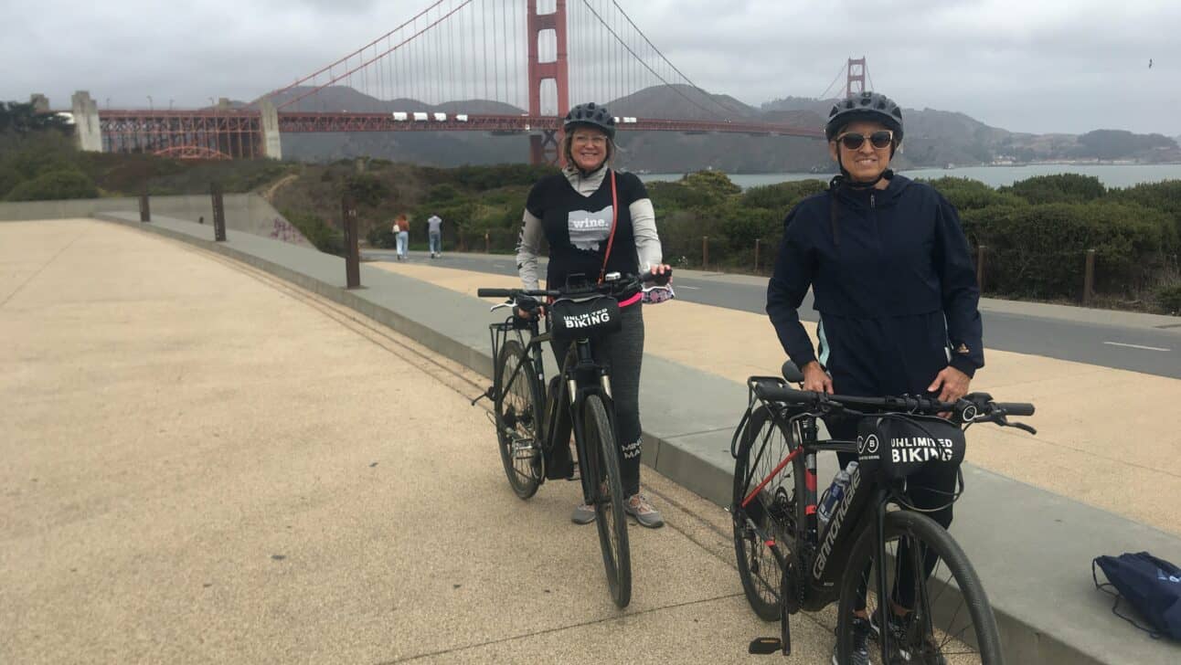A couple poses with their bikes in front of the Golden Gate Bridge in San Francisco, California