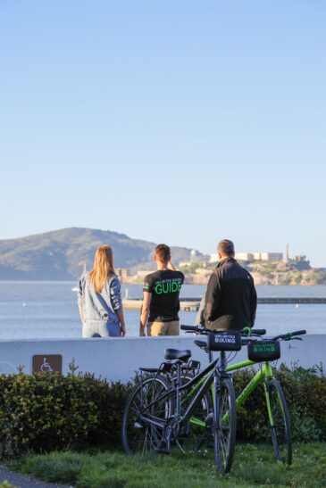 Three people look at Alcatraz from the coast