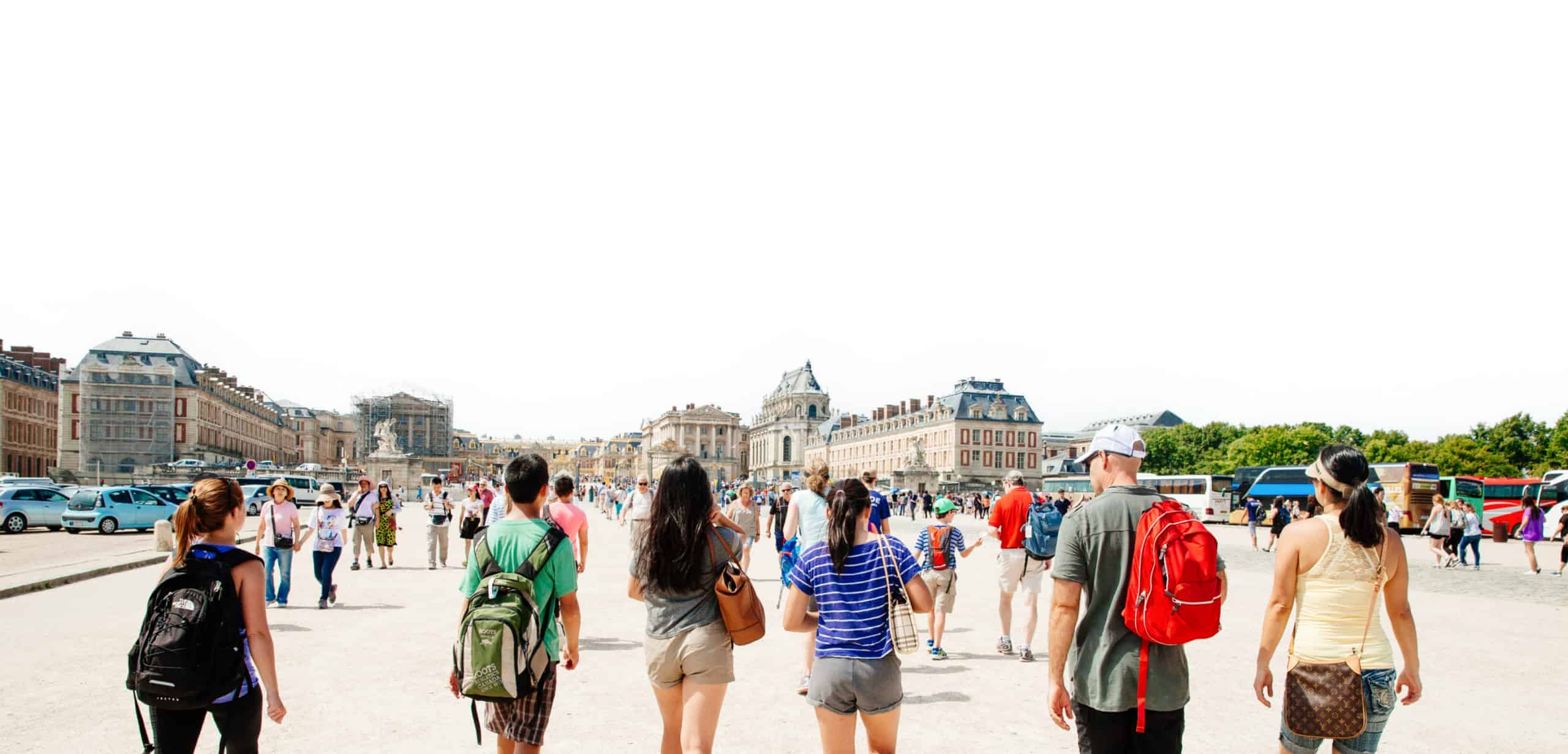 A group of people walk towards the Versailles Chateau