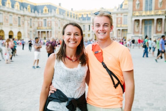 A mom and her son pose for a picture in front of the palace of Versailles