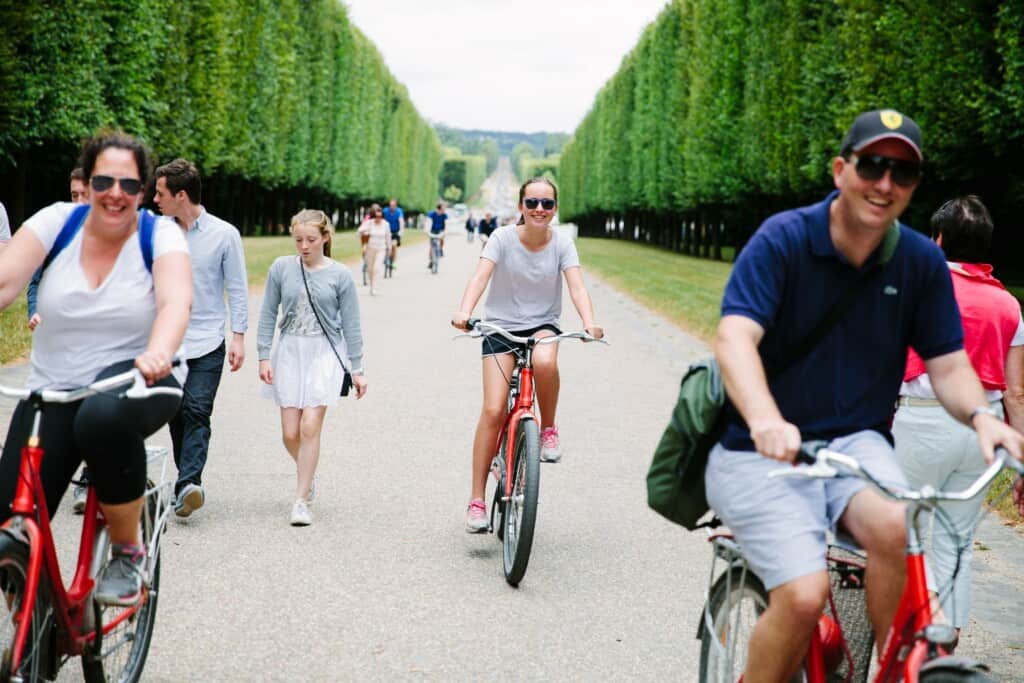 A family rides their bikes through the gardens in Versailles