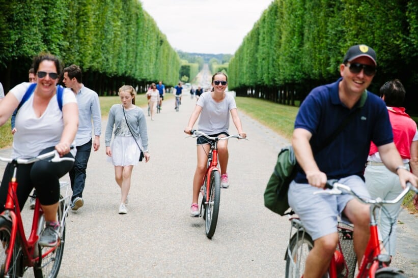 A family rides their bikes through the gardens in Versailles