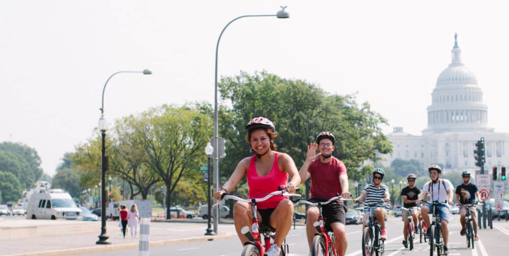 A group of cyclists ride down Pennsylvania Avenue in front of the US Capitol Building