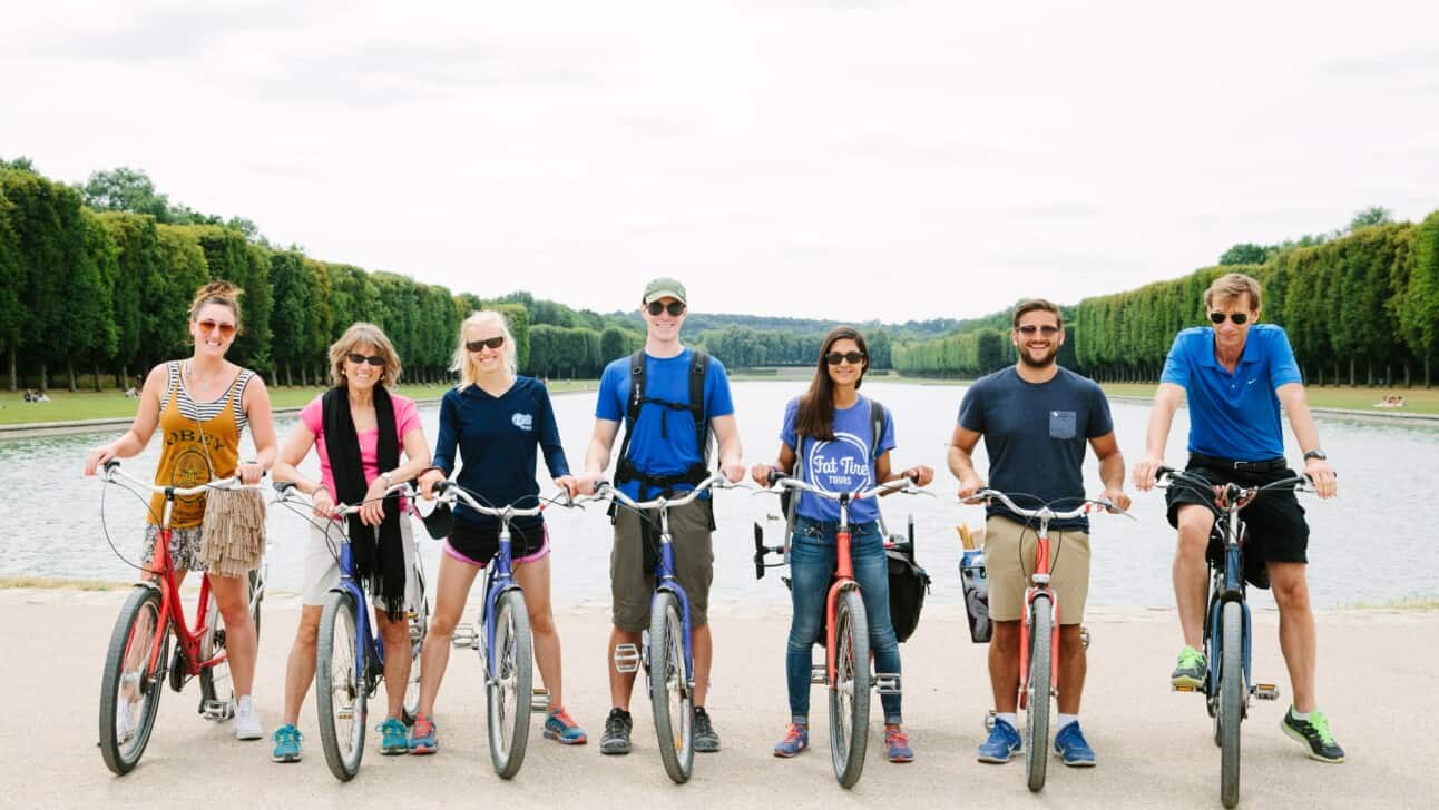 A group of cyclists poses for a photo along the Grand Canal in Versailles